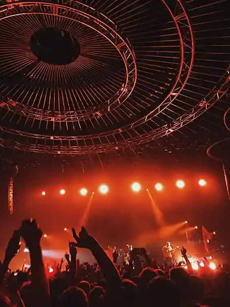 Salle de concert rouge avec le public les bras en l'air
