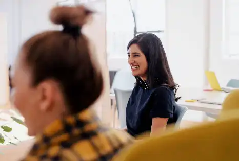 Deux femmes souriant dans un bureau de travail