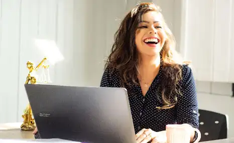 Femme avec un grand sourire, assise à un bureau avec un ordinateur
